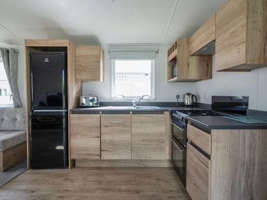 A kitchen with wooden cabinets and appliances at Billy’s Way - Hayling Island