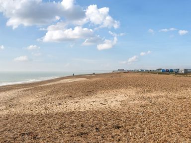 A beach with pebbles and beach huts at Billy’s Way - Hayling Island