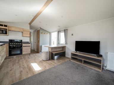A living room with a television and kitchen area at Sand and Splash - Hayling Island