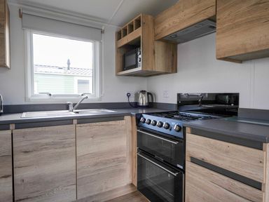 A kitchen with a sink and oven at Sand and Splash - Hayling Island