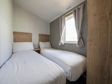 A bedroom with two single beds and a window at Sand and Splash - Hayling Island