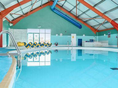 An indoor swimming pool with handrails and windows at Sand and Splash - Hayling Island