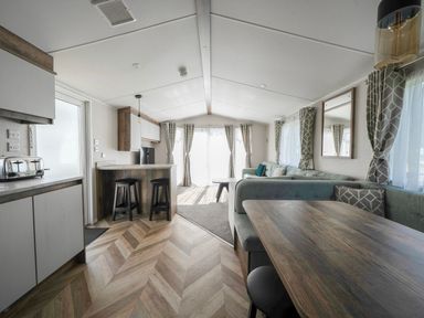 A living room with kitchen area and dining table at Wavecrest - Hayling Island