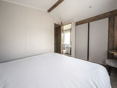 A bedroom with a bed and a bathroom visible at Wavecrest - Hayling Island