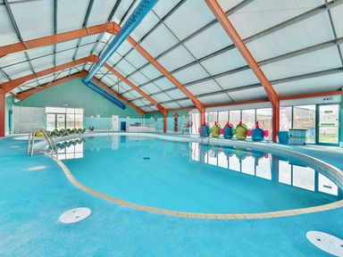 An indoor pool area with a swimming pool and exercise equipment at Wavecrest - Hayling Island