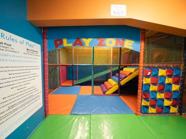 An indoor children's play area with padded floor mats, a slide, climbing steps, and a ball pocket organizer at Ripples & Reeds - Billing Aquadrome in Billing Aquadrome Holiday Park