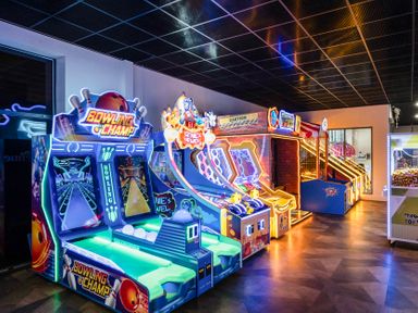 An arcade room with illuminated bowling and skee ball game machines on a wooden floor at Ripples & Reeds - Billing Aquadrome Billing Aquadrome Holiday Park