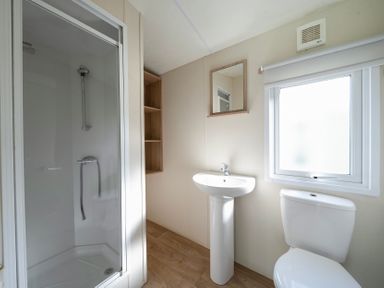 A bathroom with a shower cubicle a pedestal sink a toilet a mirror and a window at Ripples & Reeds - Billing Aquadrome in Billing Aquadrome Holiday Park