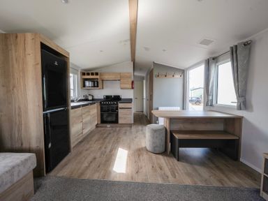 A kitchen and dining area with wooden cabinets and flooring at Kingfisher Caravan Billing Aquadrome