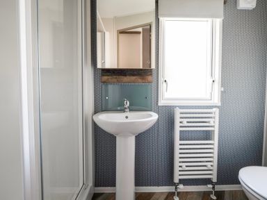 A bathroom with a sink pedestal a shower enclosure a window and a towel radiator at Stillwater Retreat - Billing Aquadrome in Billing Aquadrome Holiday Park