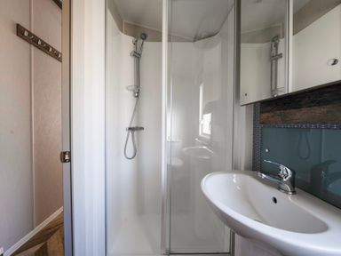A bathroom with a shower enclosure a sink and a wall-mounted cabinet at Stillwater Retreat - Billing Aquadrome in Billing Aquadrome Holiday Park