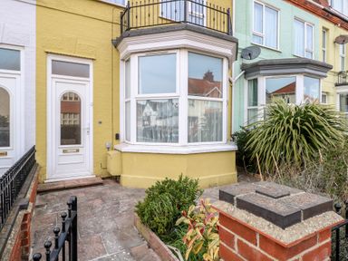 The exterior front of a yellow terraced house with a white door and bay window at 34 North Denes Road in Great Yarmouth
