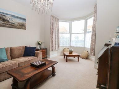 A living room with a brown sofa cushions wooden coffee tables and a bay window at 34 North Denes Road Great Yarmouth