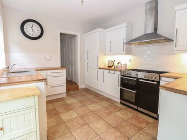 A kitchen with white cabinets wooden countertops a black double oven and a wall clock at 34 North Denes Road Great Yarmouth