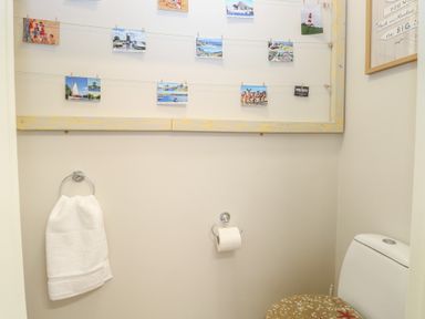 A bathroom with a toilet towel ring with a white towel and postcards on a string on the wall at 34 North Denes Road Great Yarmouth