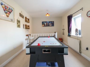 A game room with an air hockey table a stool posters on the wall a jukebox near a window at 34 North Denes Road in Great Yarmouth