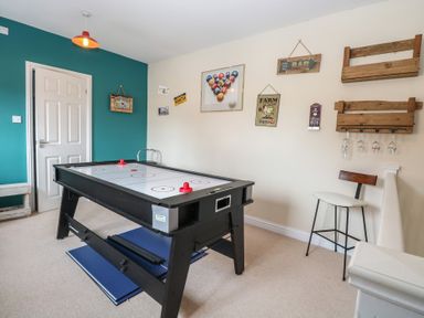 A room with an air hockey table white door teal wall chair and wall decorations at 34 North Denes Road in Great Yarmouth