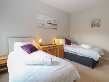 A bedroom with two single beds with white bedding and purple pillows at 34 North Denes Road in Great Yarmouth