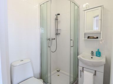 A bathroom with a toilet shower cubicle sink and mirror cabinet at 34 North Denes Road in Great Yarmouth
