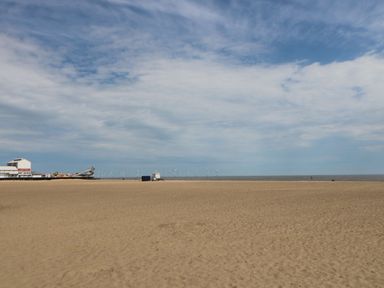 A sandy beach with a pier and wind turbines in the distance at 34 North Denes Road in Great Yarmouth