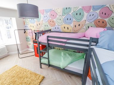 A bedroom with bunk beds and a wallpaper with colorful smiley faces at Ty Blodau near Prestatyn