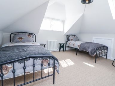 A bedroom with two single beds and small side tables near a window at Ty Blodau near Prestatyn