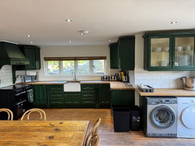 A kitchen with green cabinets white appliances wooden countertops and a wooden table at Hafod Lodge in Hensol near Pontyclun