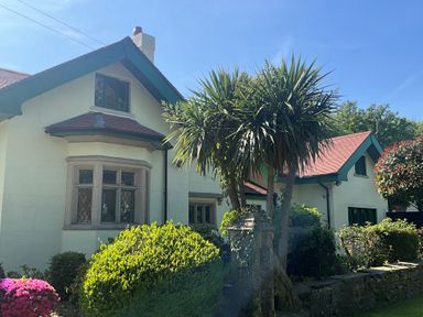 A house with a bay window surrounded by bushes and trees at Hafod Lodge in Hensol near Pontyclun