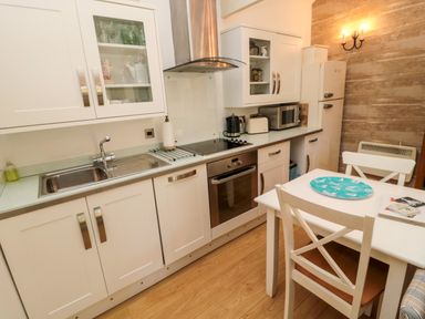 A kitchen with white cabinets dining table and chairs and appliances at The Forge Nr.Seahouses