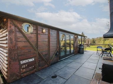 An outdoor patio area with a vintage wooden train carriage converted into a building at GWR Wagon - Victoria Station in Ludlow