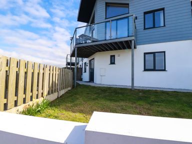 An exterior view of a modern house with a balcony and a wooden fence at Jacana in Perranporth