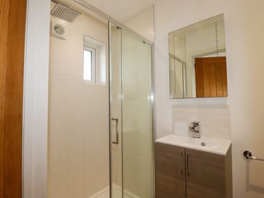 A bathroom with a shower enclosure a sink with cabinet and mirror at Jacana in Perranporth