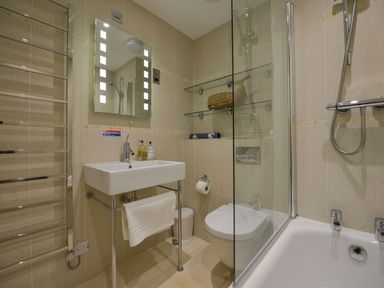 A bathroom with washbasin, toilet, shower, and shelves at Apartment 12, Burgh Island Causeway Bigbury-On-Sea