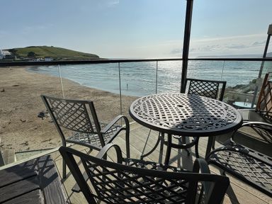 An outdoor seating area with a table and chairs overlooking the beach at 12 Burgh Island Causeway Bigbury-On-Sea