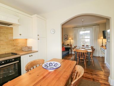 A kitchen with wooden table and chairs next to a dining area with a wooden table and chairs at Springfield in Kingsand