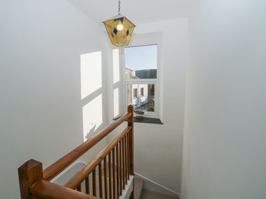 A staircase with wooden railing and window with a model ship on the sill at Springfield in Kingsand
