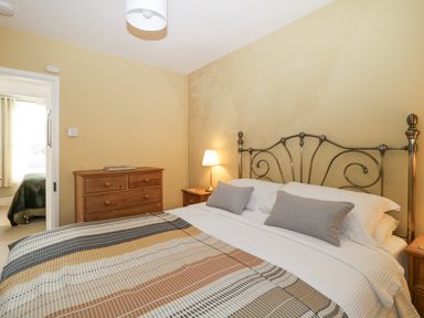 A bedroom with a bed a patterned blanket wooden dressers and a lamp at Springfield in Kingsand
