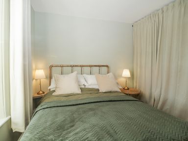 A bedroom with a bed with pillows and blankets and two bedside tables with lamps at Springfield in Kingsand