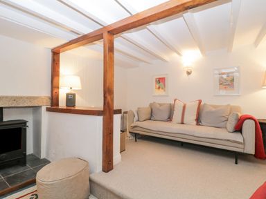 A living room with a beige sofa cushions a wood burning stove and a lamp at Springfield in Kingsand
