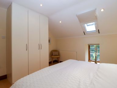A bedroom featuring a wardrobe, bed, chair, and window at Heathcliffe House Castleton near Cardiff