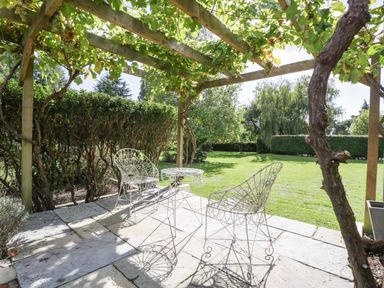 A garden with a table and two chairs under a vine pergola at Heathcliffe House Caslteton near Cardiff