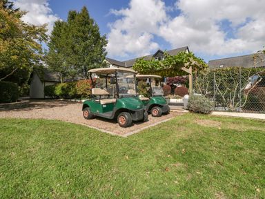 Two golf carts parked on gravel with trees and a building at Heathcliffe House in Castleton near Cardiff