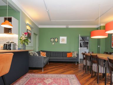 A living room with a gray sofa orange lights and a wooden dining table at Sycamore Apartment in Lifton