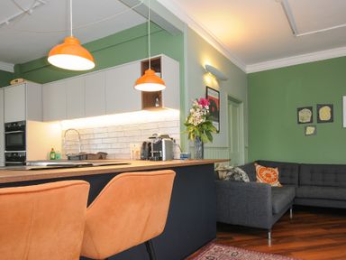 A kitchen and living area with orange chairs green walls and a gray sofa at Sycamore Apartment in Lifton