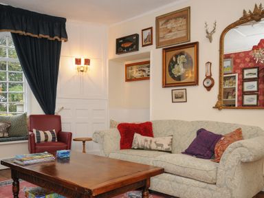 A living room with a sofa and armchair with cushions a wooden coffee table and wall art at Sycamore Apartment in Lifton