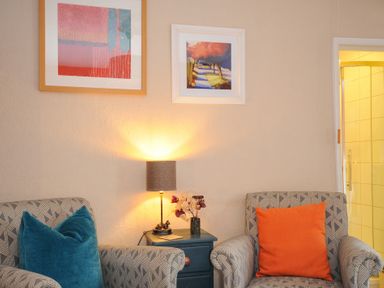 Two armchairs with cushions and a side table with a lamp and flowers in a room at Sycamore Apartment in Lifton