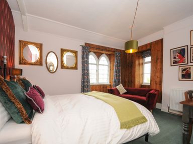 A bedroom with a bed with green and purple pillows a green throw a red sofa and three mirrors on the wall at Sycamore Apartment Lifton