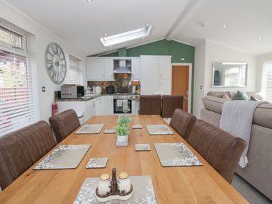 A dining area with wooden table set with placemats and a small plant in a kitchen living space at Swifts Reach Lodge Kirkstone 10 Limefitt Park near Windermere