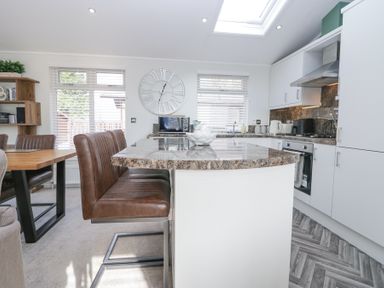 A kitchen with a marble countertop island and brown leather chairs at Swifts Reach Lodge Kirkstone 10 Limefitt Park near Windermere