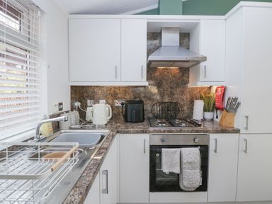 A kitchen with a sink a dish rack a kettle a toaster an air fryer a stove an oven and knives at Swifts Reach Lodge Kirkstone 10 Limefitt Park near Windermere